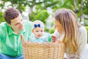 Happy couple with their baby in a laundry basket
