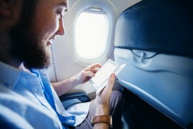 Man holding a smart phone with blank screen in airplane. Templat